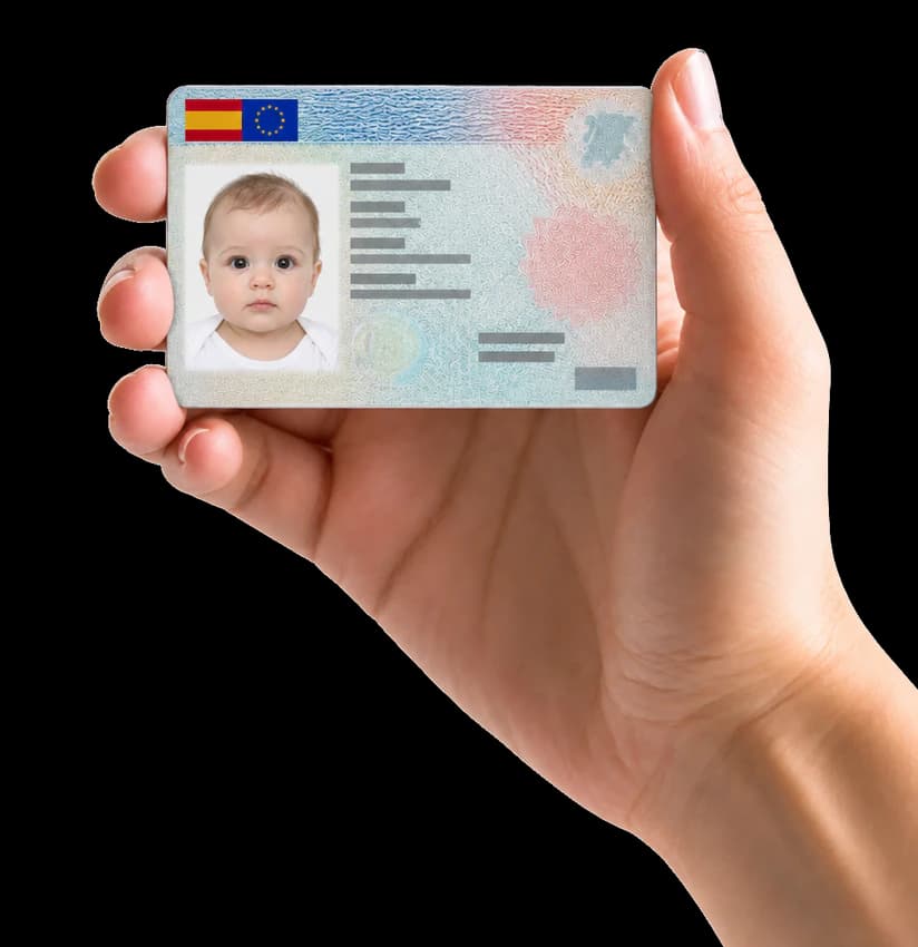 Mano sujetando un DNI con la foto de carnet de un bebé, de 26 × 32 mm
